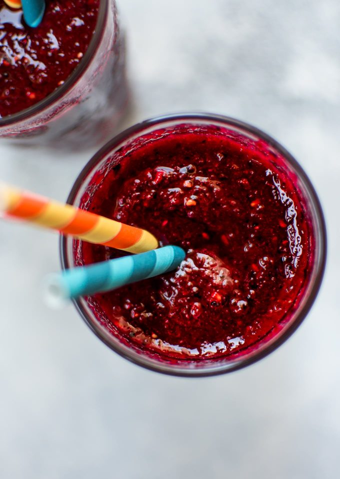 close-up of beet and berry smoothie in a glass with two straws