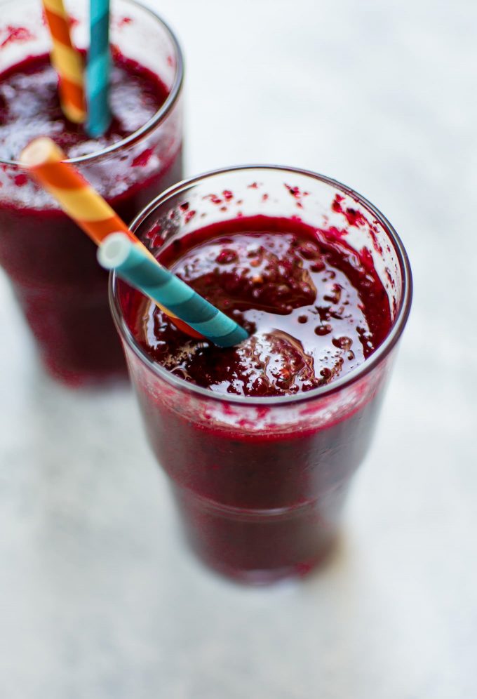 two glasses of healthy beet and berry smoothie with straws
