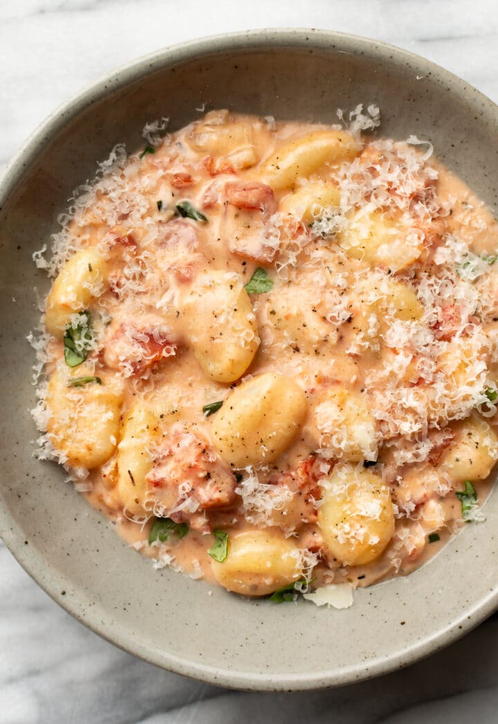a bowl of creamy tomato gnocchi with grated parmesan