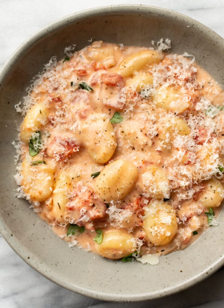 a bowl of creamy tomato gnocchi with grated parmesan