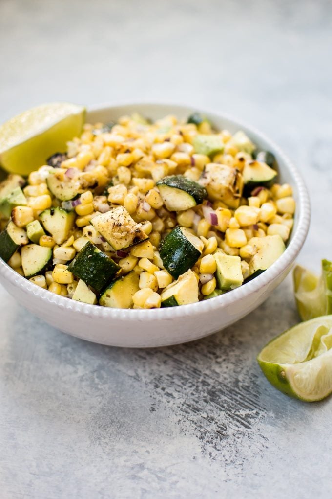 bowl of easy grilled corn and zucchini salad with lime wedges