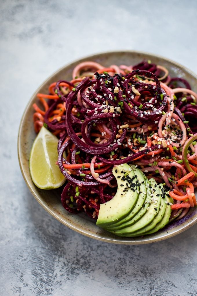 bowl of rainbow noodle salad with avocado slices