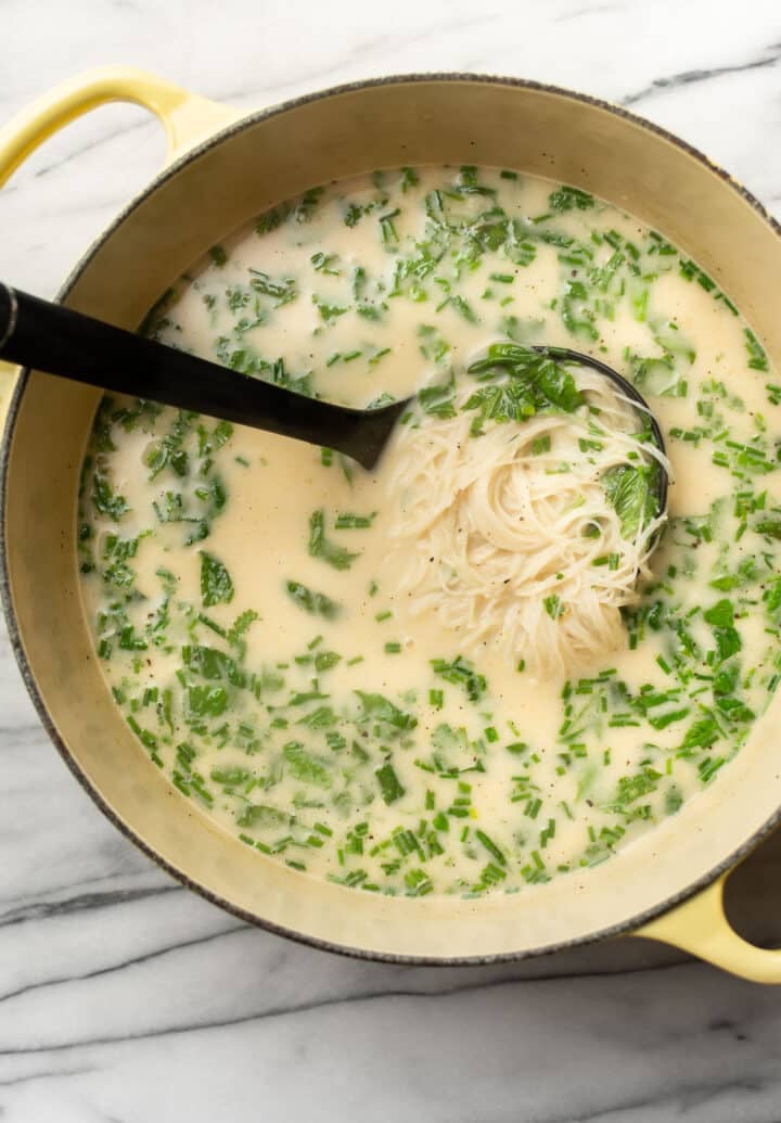 a pot of vegan thai coconut soup with a ladle