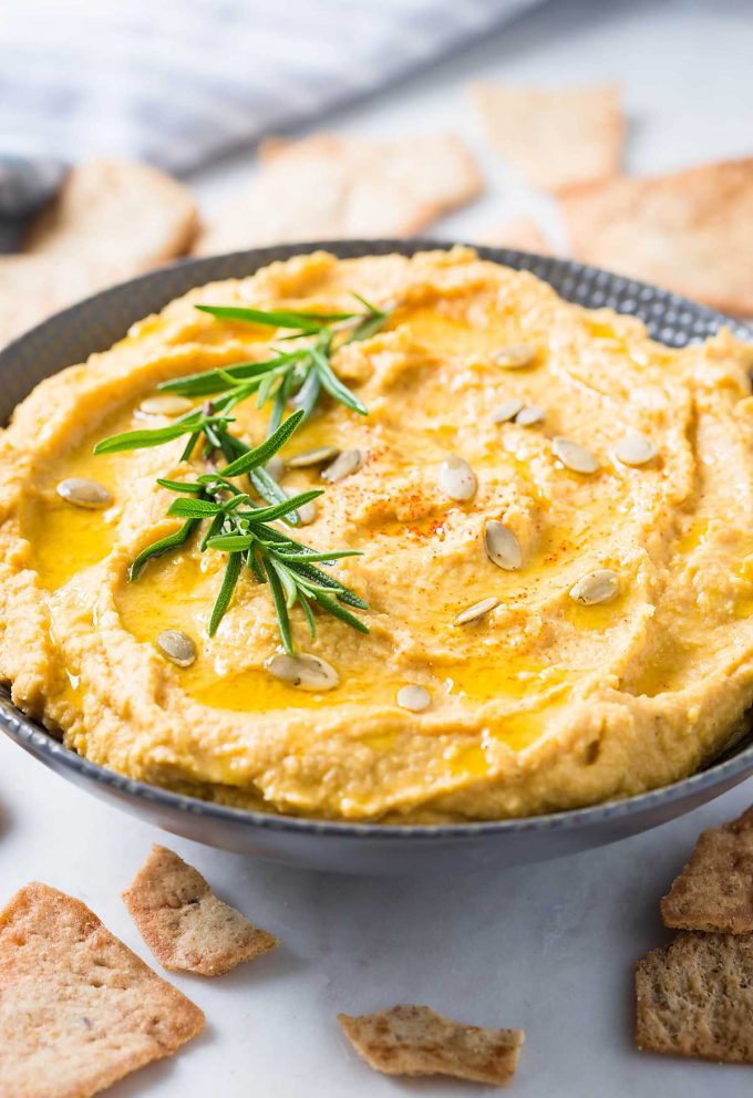 roasted garlic pumpkin hummus in a bowl beside crackers