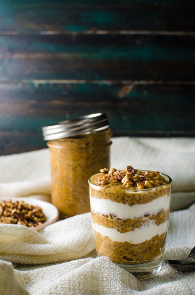 pumpkin pie chia parfait in a glass with a mason jar in the background