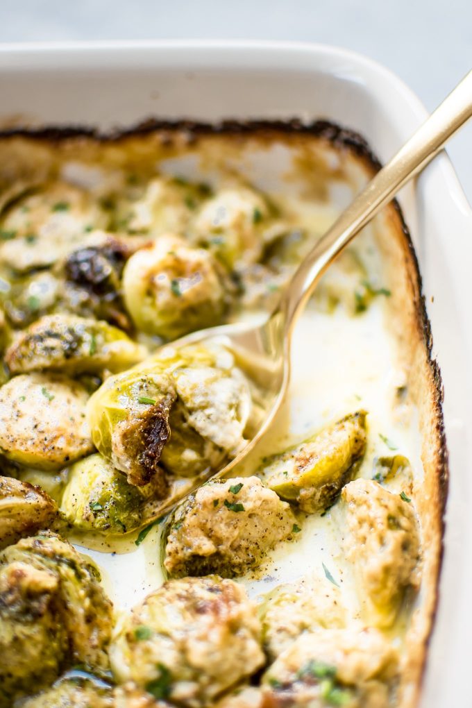 close-up of creamy garlic Brussels sprouts with a serving spoon
