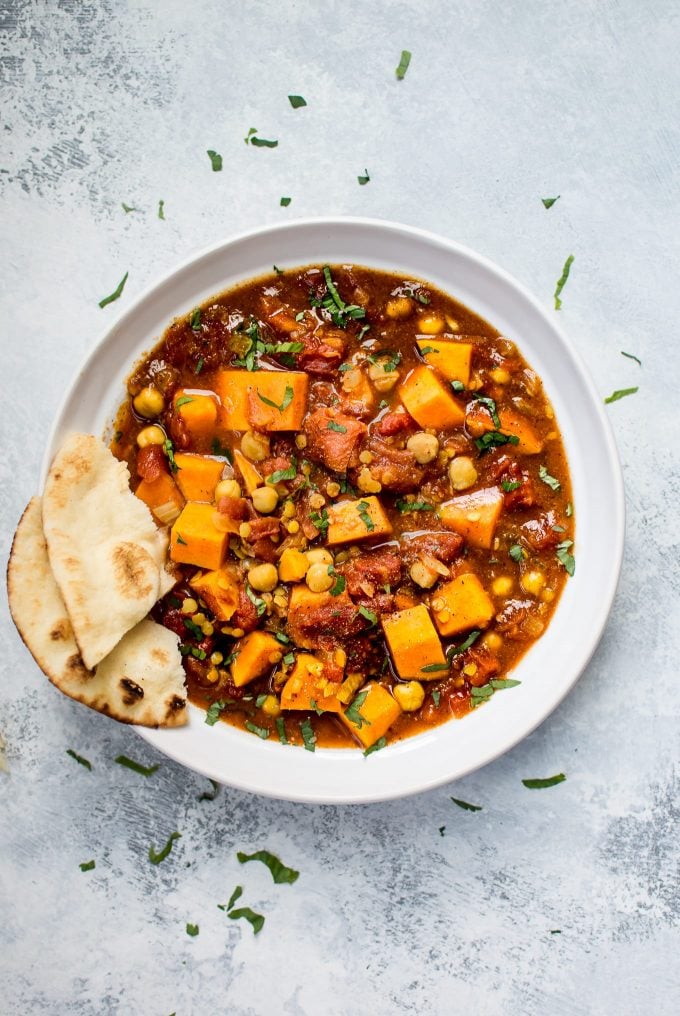 sweet potato curry in a bowl with slice of pita bread