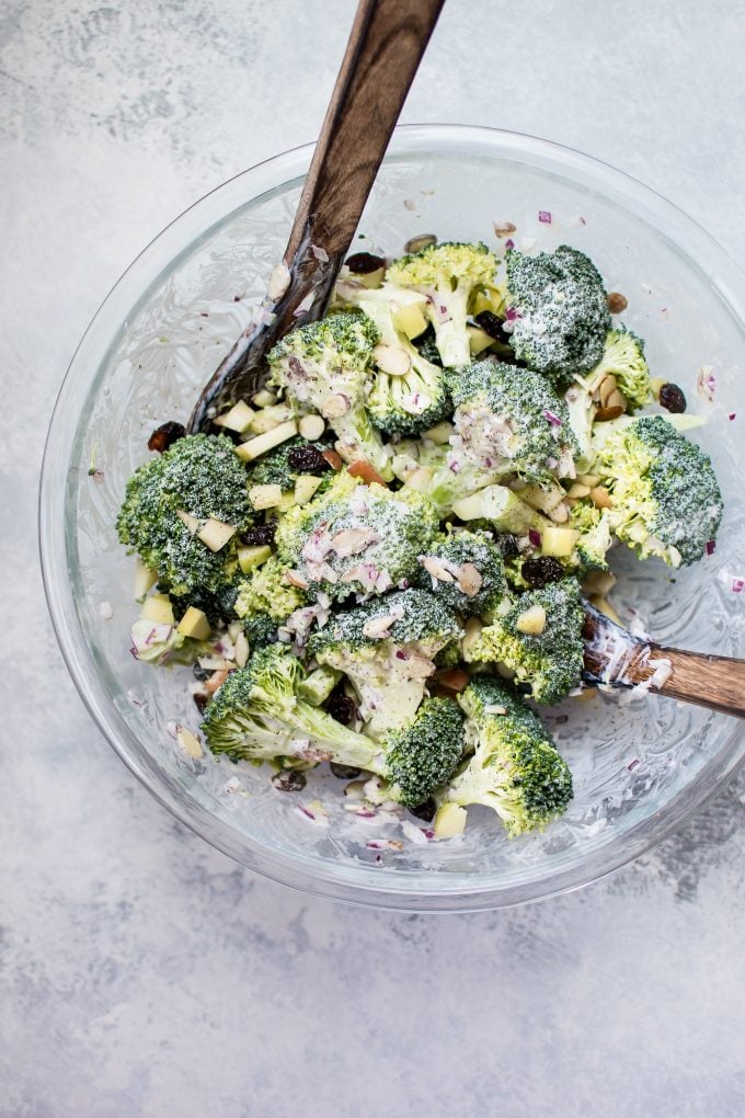 glass bowl with healthy broccoli salad and wooden salad utensils