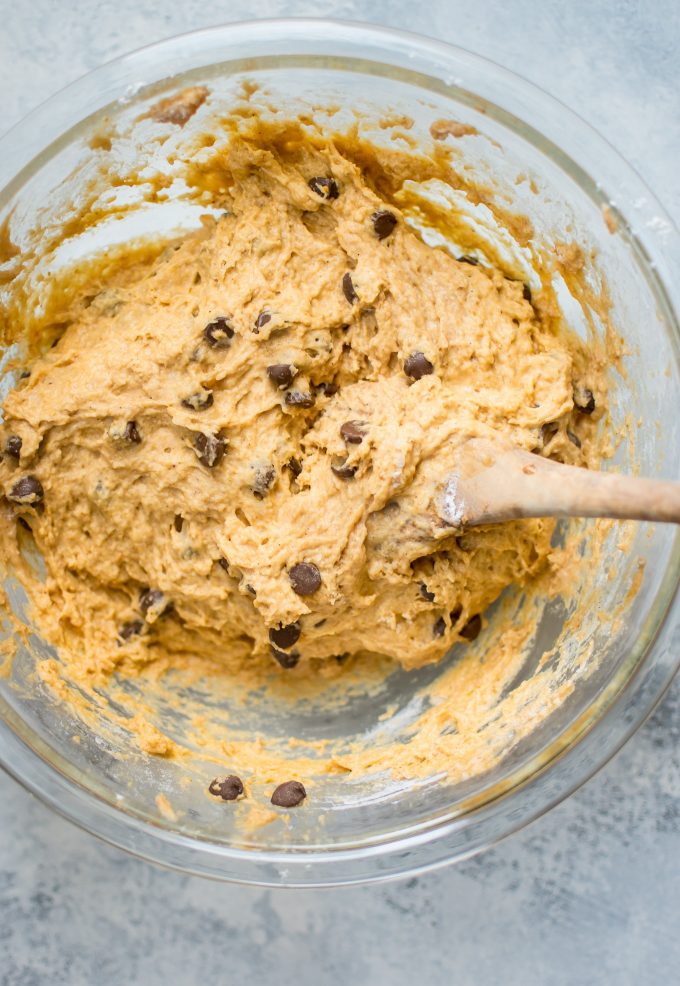 batter for pumpkin chocolate chip muffins in a glass bowl with wooden spoon