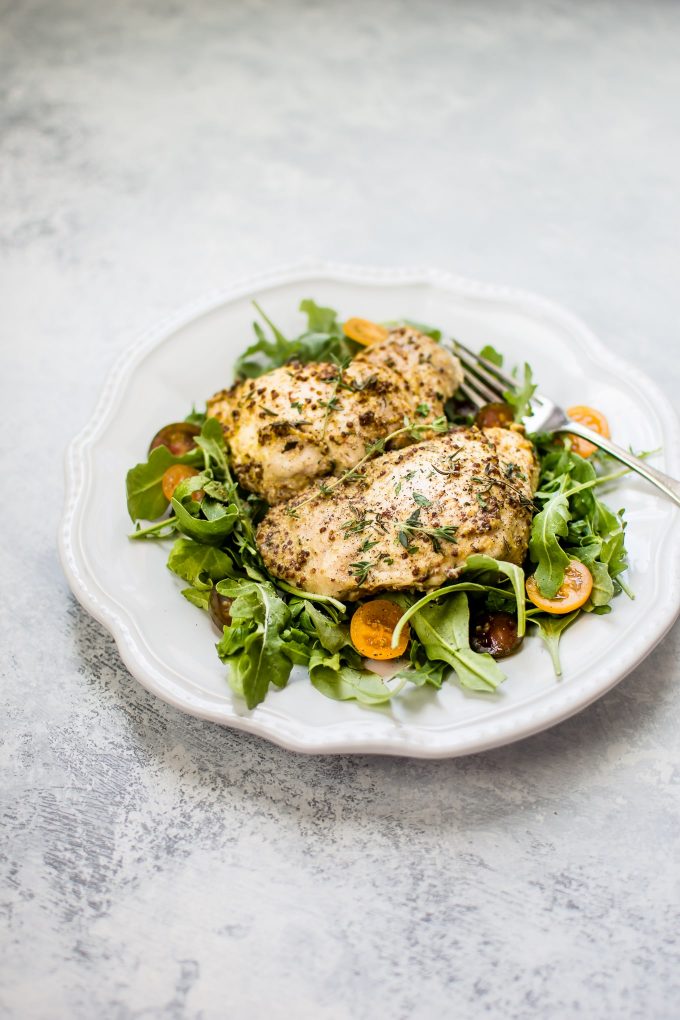 roasted mustard chicken thighs on a plate over salad greens with a fork