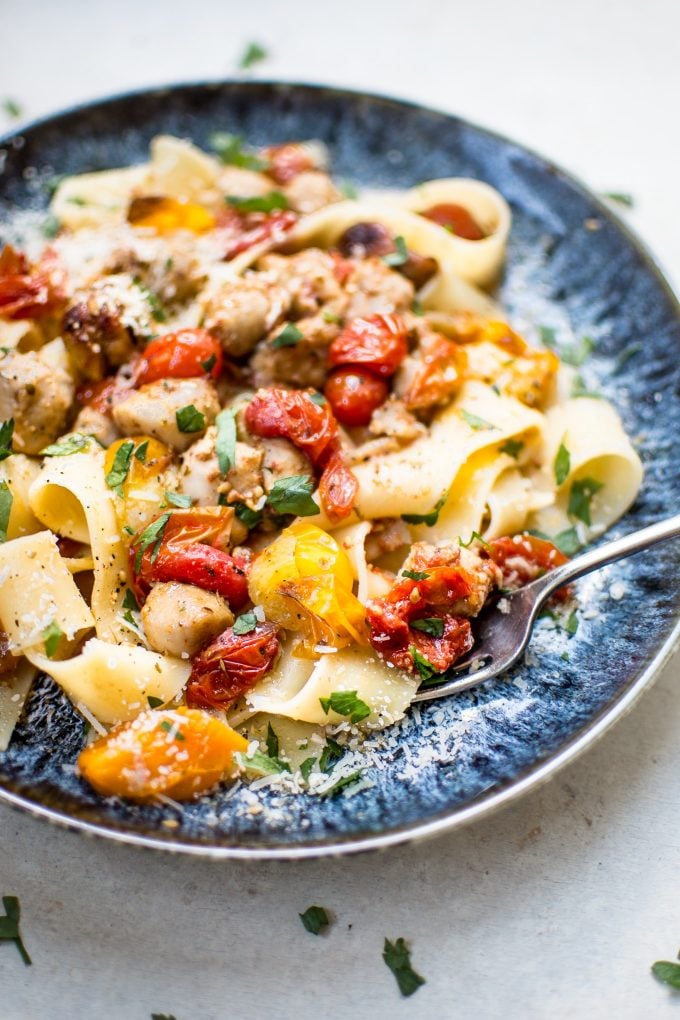 close-up of healthy chicken sausage pasta with roasted tomatoes on a plate with a fork