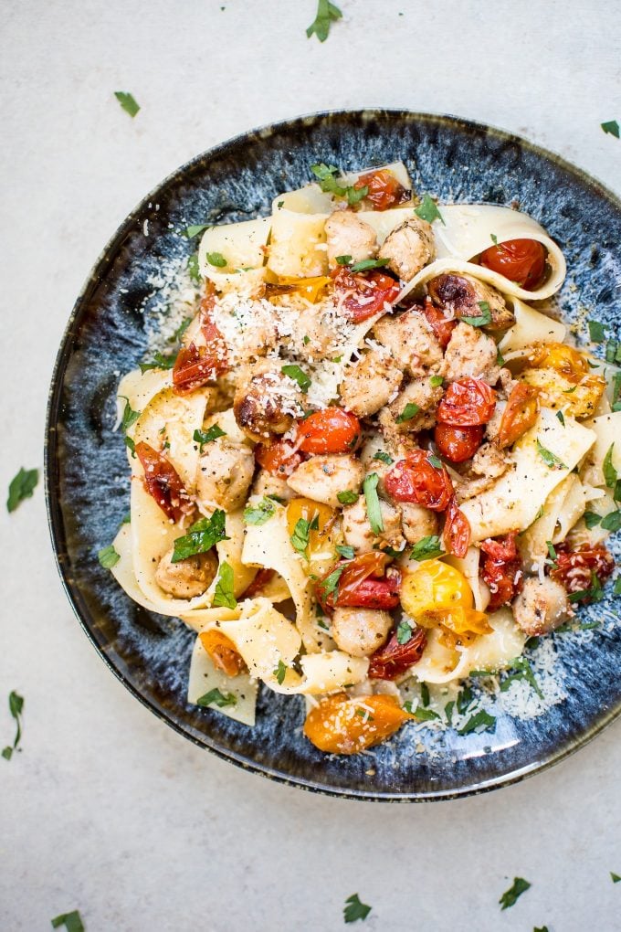 healthy chicken sausage pasta with roasted tomatoes on a plate with grated parmesan