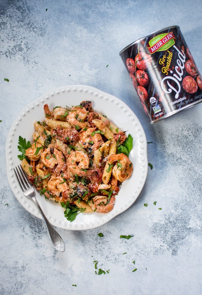 bowl of spicy shrimp pasta with roasted tomato sauce next to a can of diced tomatoes