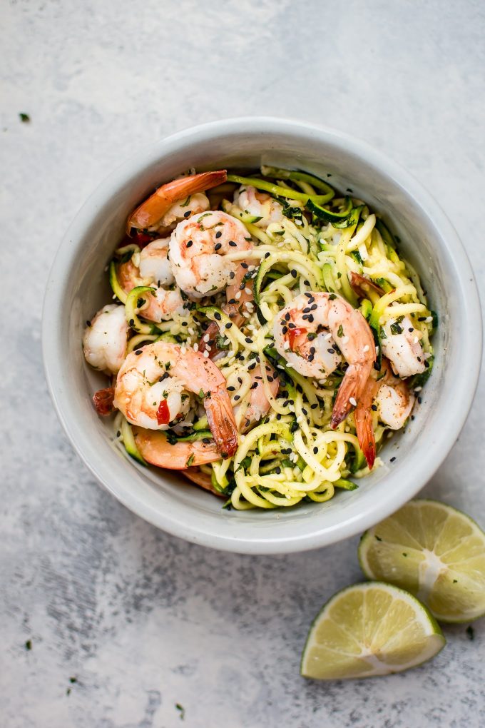 sweet chili shrimp zoodles in a bowl beside lime wedges