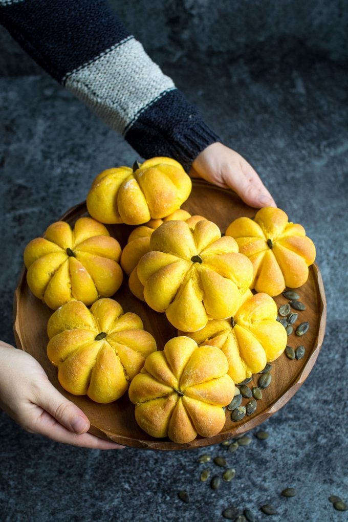 hands holding tray of several pumpkin rolls