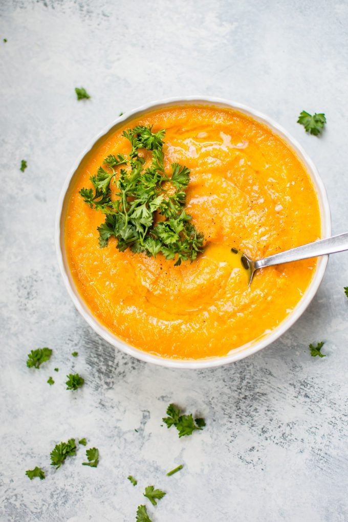 bowl of vegetarians carrot and celery root soup with soup and topped with parsley