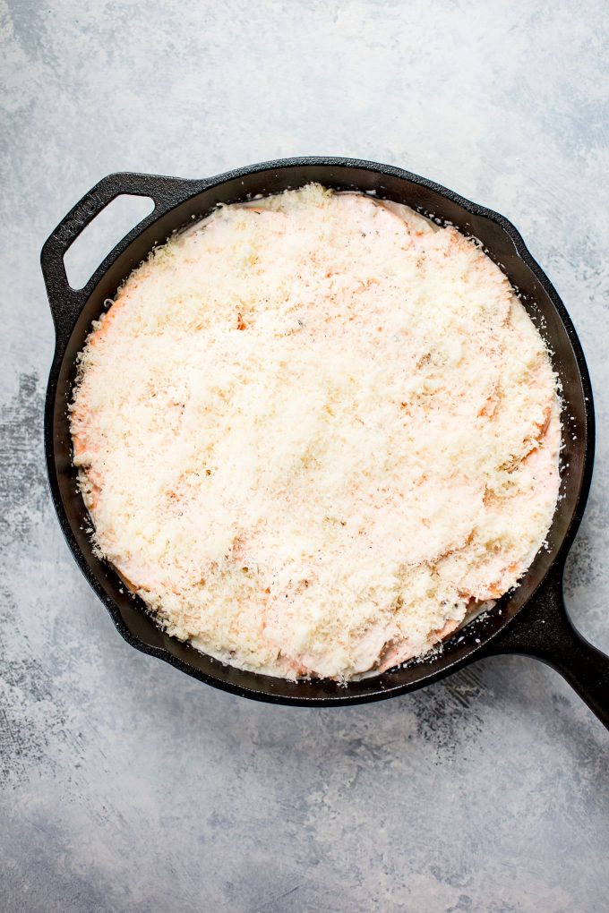 process photo of scalloped sweet potatoes in a cast iron skillet showing layer of cheese