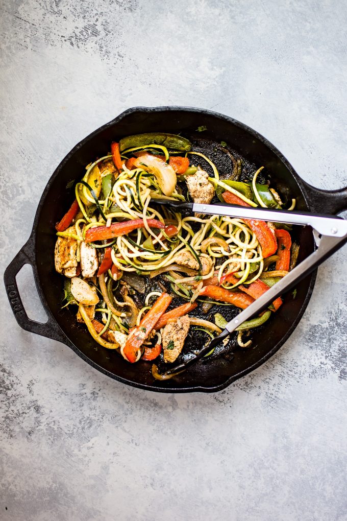 skillet with chicken fajita zoodles and tongs
