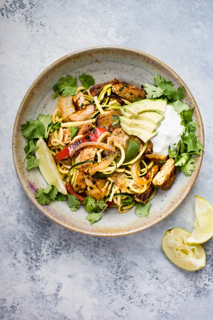 bowl with chicken fajita zoodles topped with avocado, lime, cilantro, and Greek yogurt