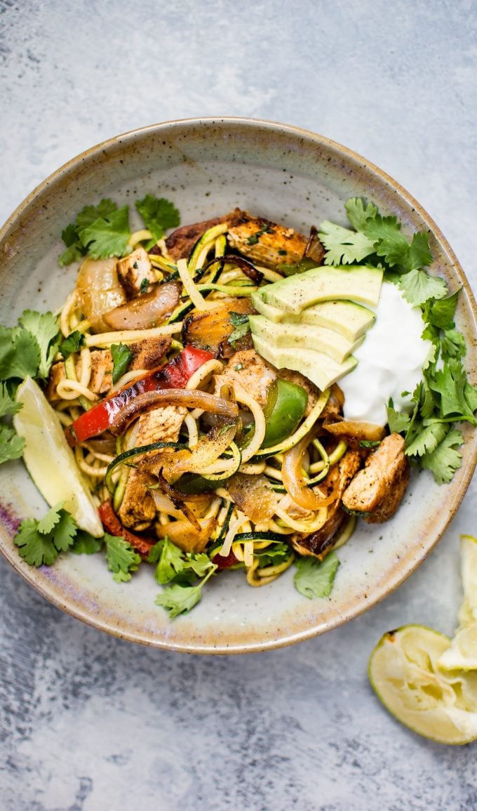 bowl of chicken fajita zoodles with sliced avocado, Greek yogurt, and fresh cilantro