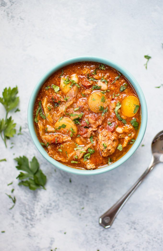 bowl of Crockpot cabbage soup beside parsley sprigs and a spoon