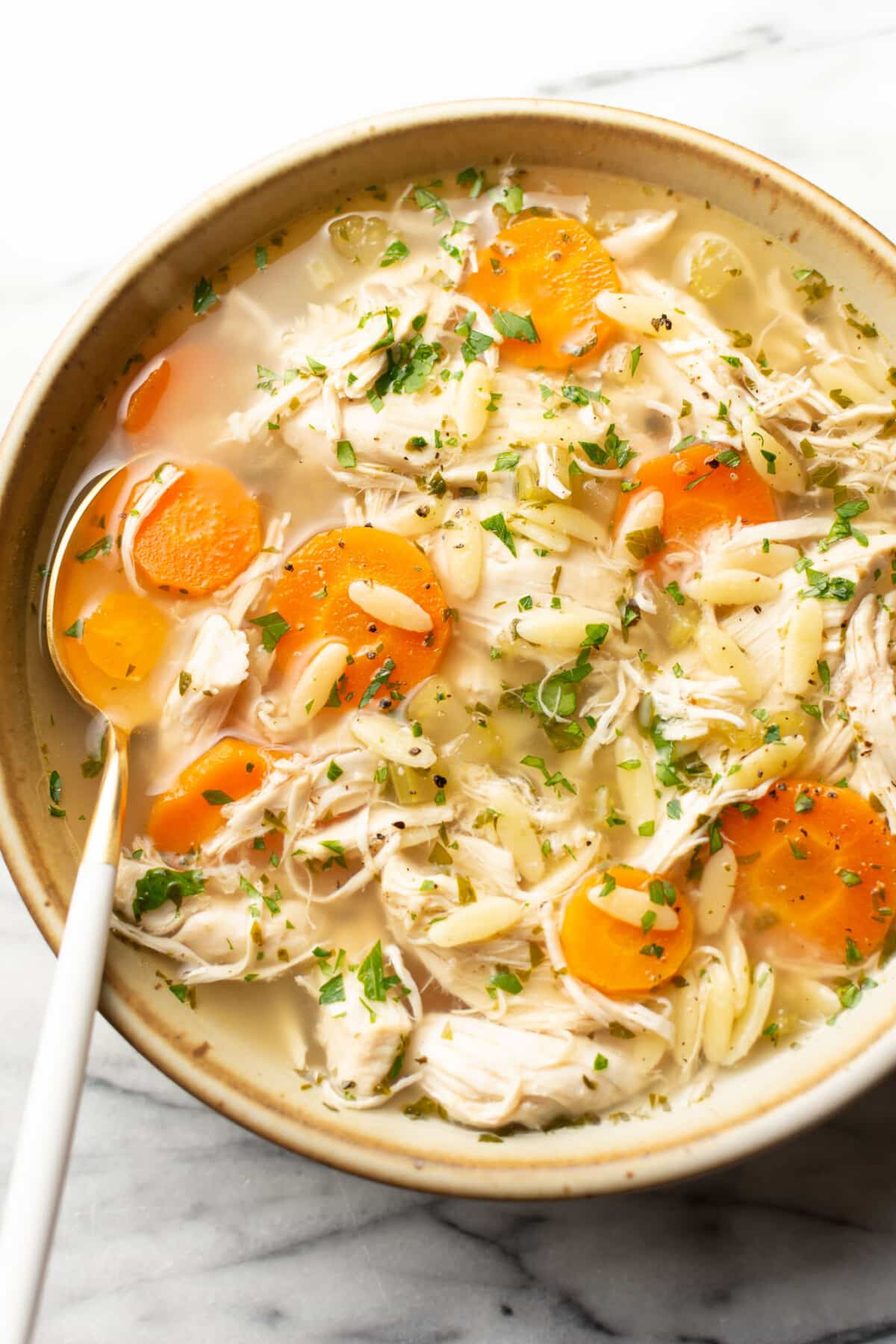 a bowl of crockpot lemon chicken orzo soup with a spoon