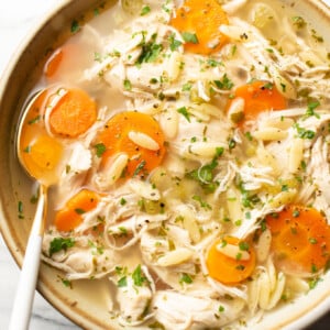 a bowl of crockpot lemon chicken orzo soup with a spoon