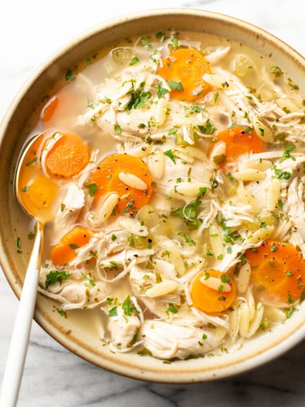 a bowl of crockpot lemon chicken orzo soup with a spoon