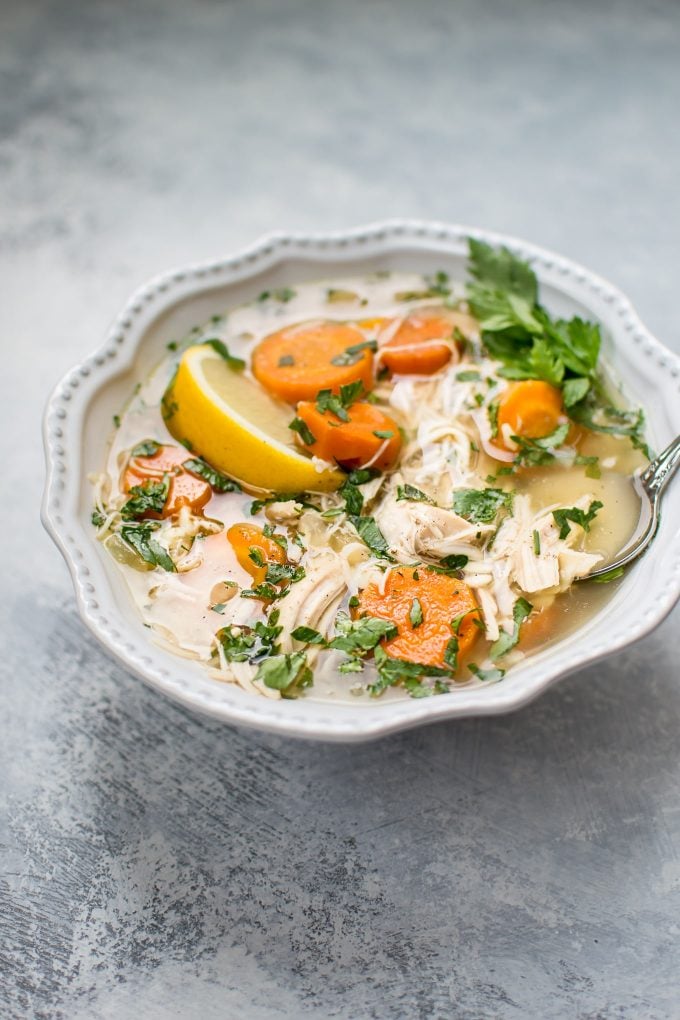 bowl of Crockpot lemon chicken orzo soup with lemon wedge garnish