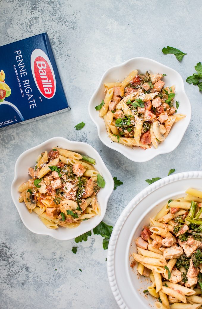 two bowls of lighter chicken and bacon pasta, box of Barilla pasta, and serving bowl of pasta