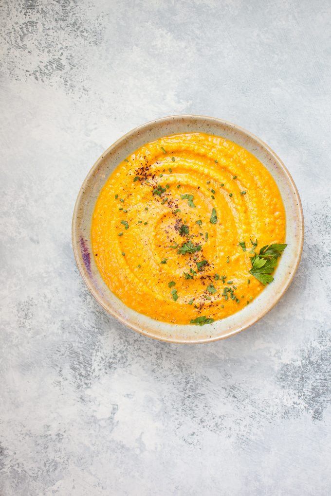 bowl of lentil pumpkin soup topped with parsley and chives