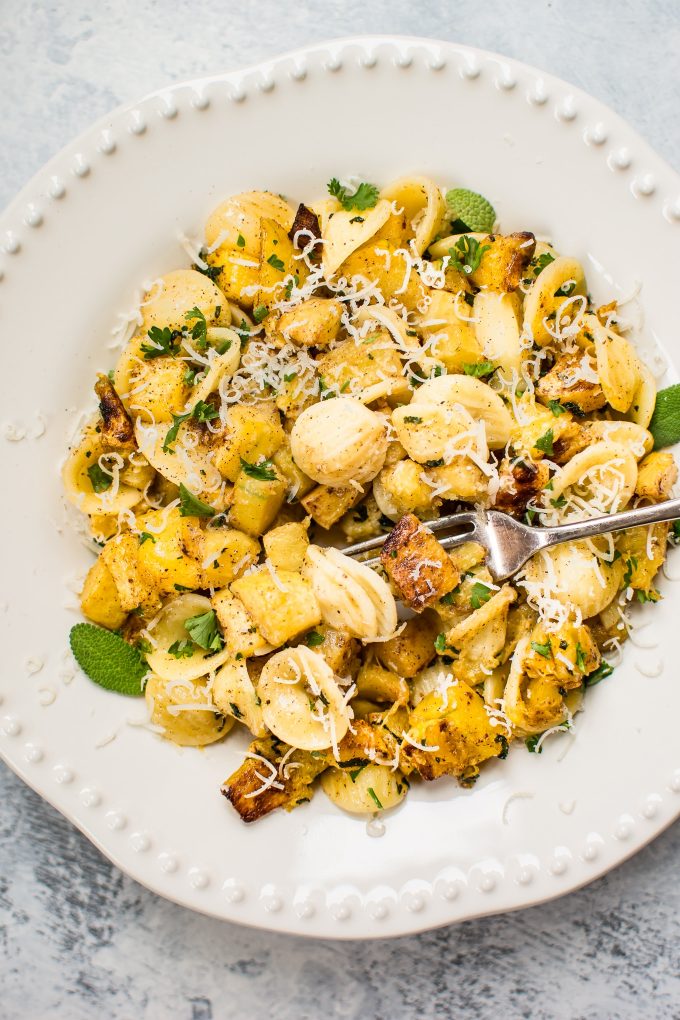 close-up of roasted butternut squash pasta in a bowl with a fork and grated cheese