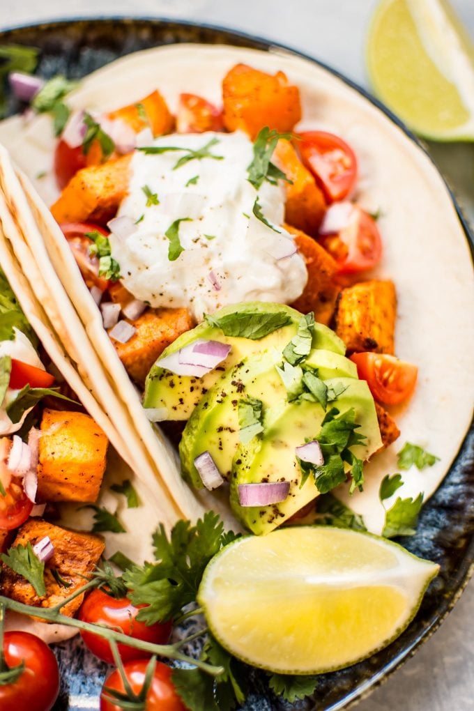close-up of roasted sweet potato taco topped with avocado and red onions