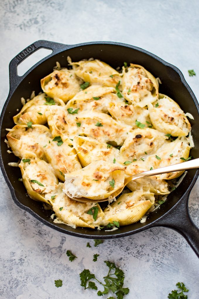 cast iron skillet with chicken stuffed shells and a serving spoon