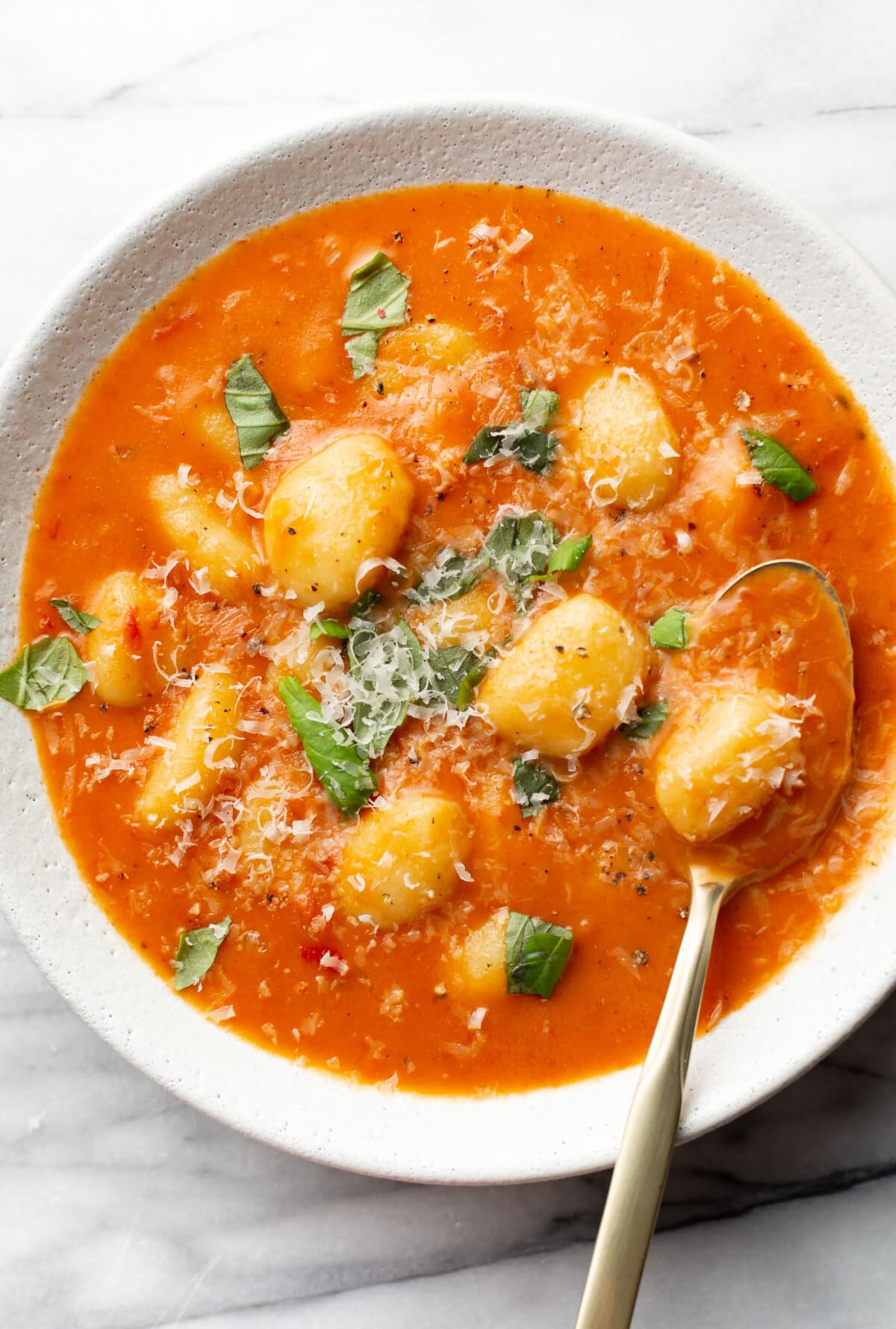 a bowl of creamy tomato gnocchi soup with a spoon