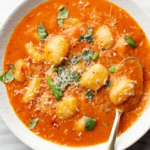 a bowl of creamy tomato gnocchi soup with a spoon