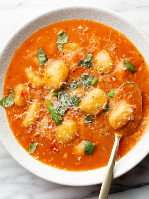 a bowl of creamy tomato gnocchi soup with a spoon