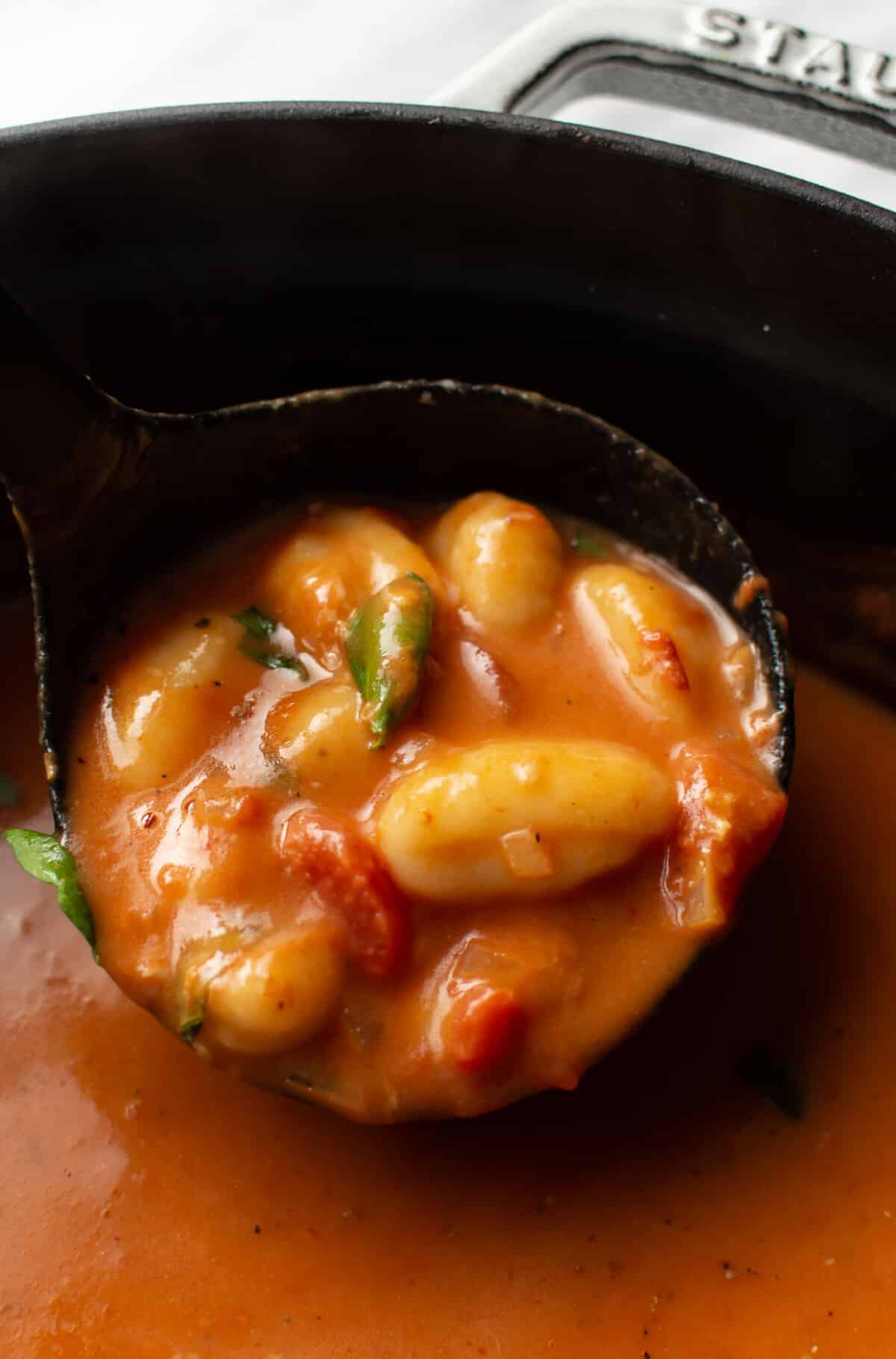 a ladleful of creamy tomato gnocchi soup