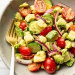 a bowl of cucumber tomato avocado salad with a fork