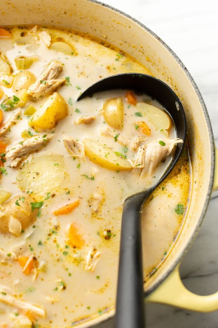a pot of leftover turkey soup with a ladle