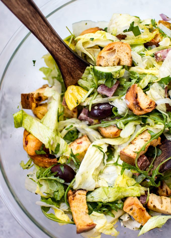 glass bowl with Italian salad and wooden salad utensils