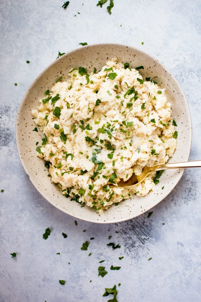 mashed parsnips with garlic and chives in a bowl with a spoon