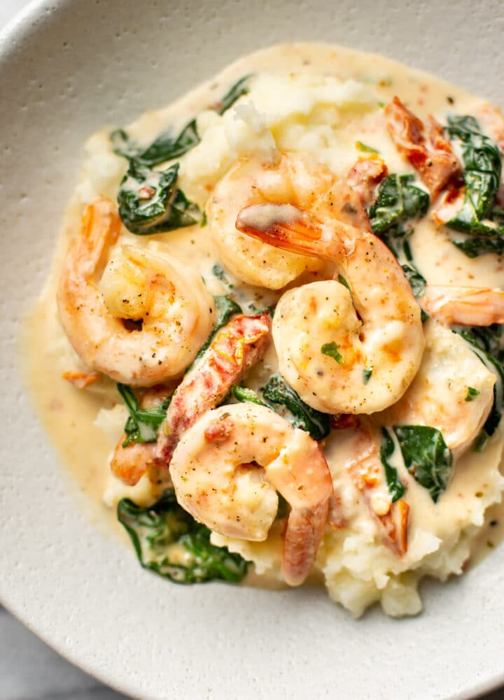 a plate with creamy tuscan shrimp over mashed potatoes