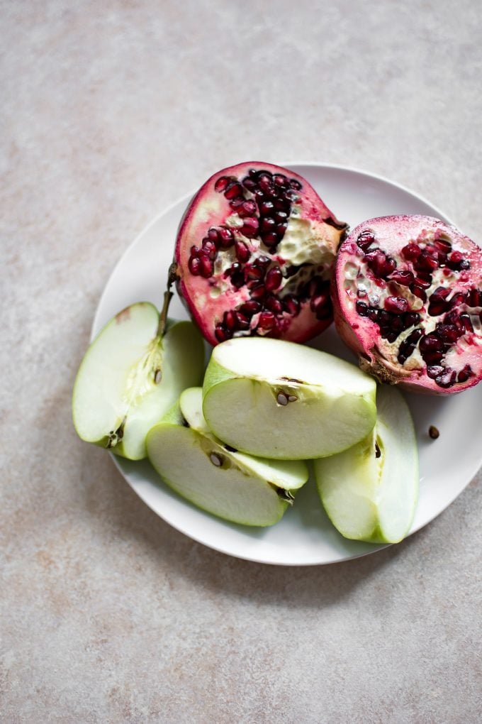 apple slices and pomegranate on a white plate