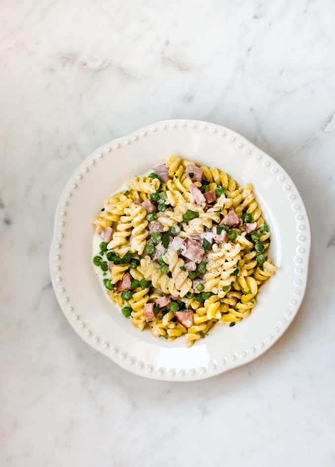bowl of one-pot ham and pea pasta on a marble surface