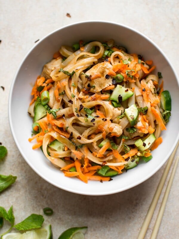 This healthy chicken stir fry with rice noodles is quick and delicious. Perfect for easy weeknight dinners! Garnished with scallions, mint, grated carrots, and cucumber.