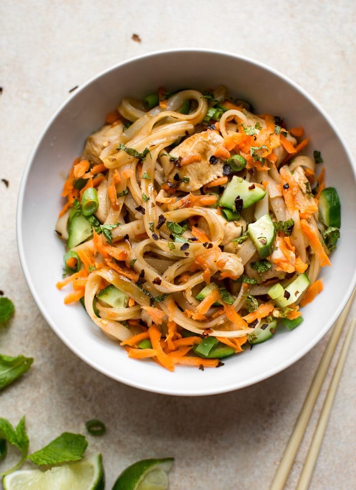 This healthy chicken stir fry with rice noodles is quick and delicious. Perfect for easy weeknight dinners! Garnished with scallions, mint, grated carrots, and cucumber.