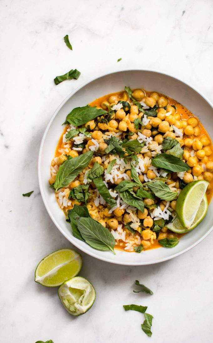 a white plate with chickpea coconut curry and lime wedges