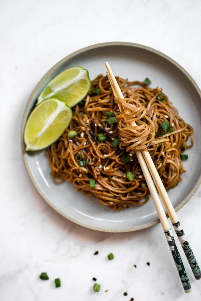 easy chili garlic noodles on a plate with chopsticks with two lime wedges