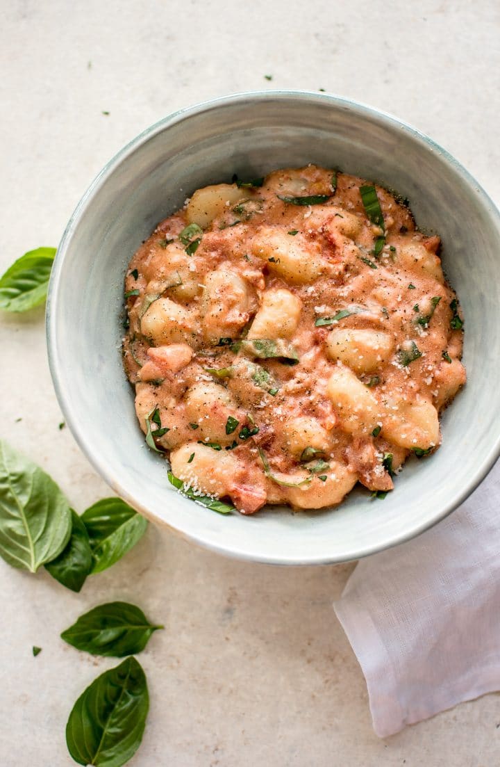 bowl of gnocchi alla vodka in bowl beside basil leaves